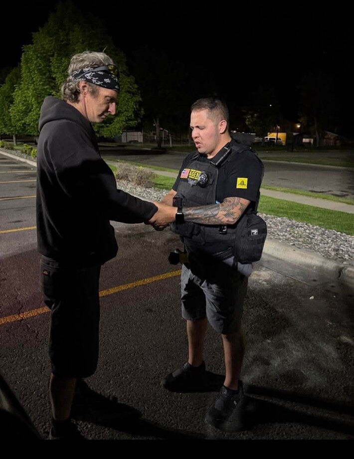 Joel Graf holding a man's hands in prayer outdoors at night.