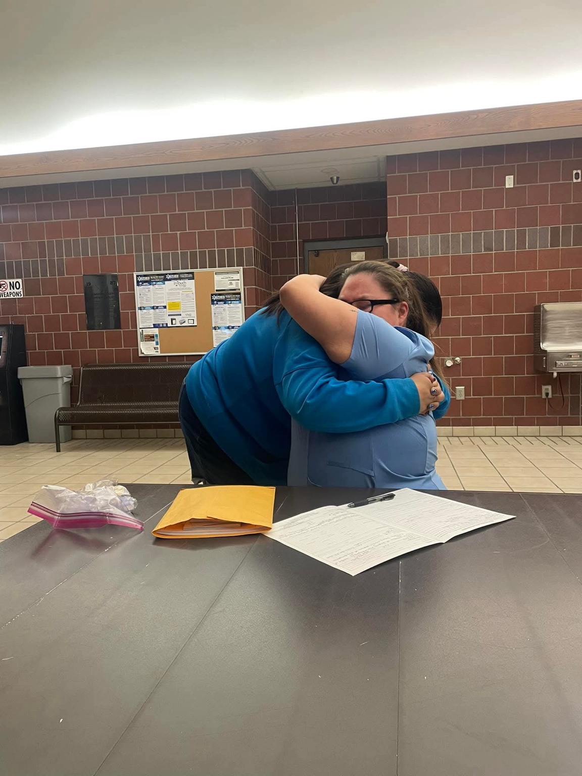 A human moment during Northwest Bail Bonds work Two people sharing an embrace across a table with paperwork at a Montana detention facility.